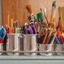 Organized art supplies including brushes, scissors, and pencils in metal containers.
